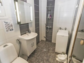 Een badkamer met een wastafel, spiegel, douche, toilet en bidet.