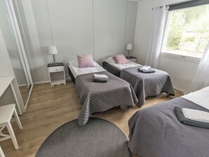 Een slaapkamer met twee bedden, een nachtkastje, een bureau en een raam met gordijnen.