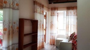 Une pièce comprenant un lit, un canapé, une bibliothèque en bois et une fenêtre avec des rideaux.