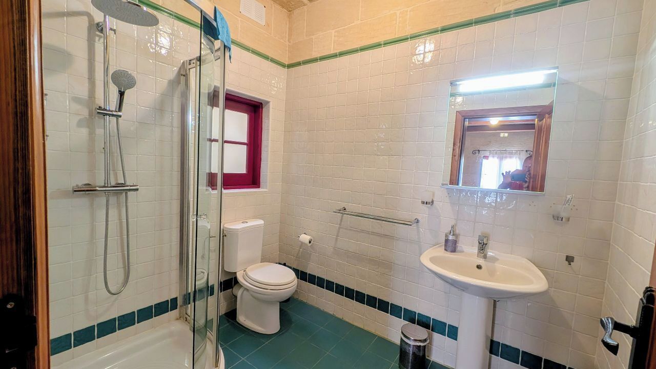 A bathroom with a shower, toilet, sink, and mirror.