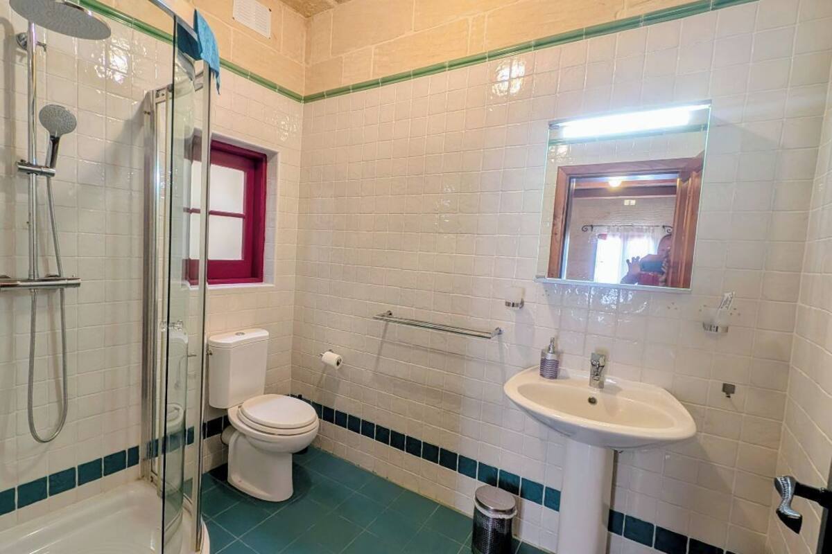 Une salle de bain équipée d’une douche, de toilettes, d’un lavabo et d’un miroir.