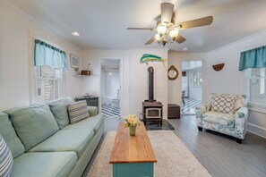 A living room with a sofa, armchair, wooden coffee table, and a fireplace. - Incredible Screened Porch - Stay with Seaside Vacations! (Chincoteague Island)