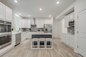 A modern kitchen with white cabinetry, stainless steel appliances, a central island, and a bench. - Great Amenities + Dog Friendly! (Greenbackville)