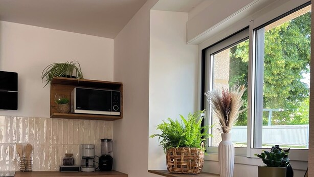 Una cucina moderna con mobili bianchi, un forno a microonde e una macchina da caffè sul piano di lavoro.