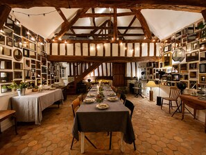 Ein Essbereich mit langem Tisch, gedeckt für eine Mahlzeit, umgeben von Holzbalken und Steinwänden.