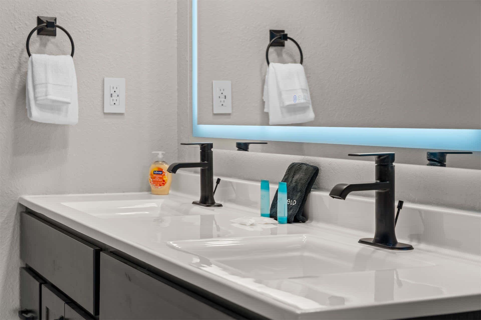 A bathroom with two sinks, a mirror, and a towel rack.
