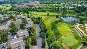 Een golfbaan met een vijver, omringd door woongebouwen en een groot hotel.