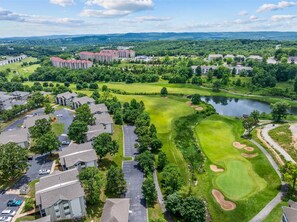 A golf course with a pond, surrounded by residential buildings and a large hotel. - Green Mountain Getaway 2bdr (Branson)