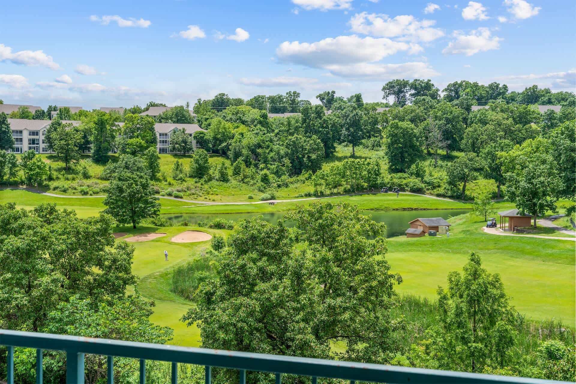 A golf course with bunkers, a pond, and a clubhouse.