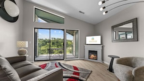 Een moderne woonkamer met een open haard, een televisie en een balkon met uitzicht.