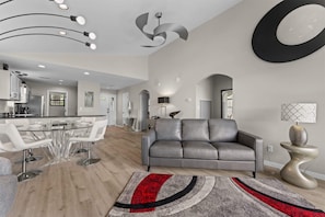A modern living room with a grey leather sofa, a dining area with a glass table, and a kitchen with white cabinets. - Green Mountain Getaway 2bdr (Branson)