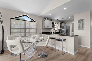 A modern kitchen with a central island, white cabinetry, and stainless steel appliances. - Green Mountain Getaway 2bdr (Branson)