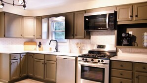 A modern kitchen with a built-in microwave, stove, dishwasher, and a window above the sink. - Dover Den in the Bend - Hot Tub and Pet Friendly! (South Bend)