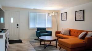 A living room with a sofa, armchair, coffee table, and a door. - Dover Den in the Bend - Hot Tub and Pet Friendly! (South Bend)