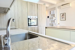 A modern kitchen with a stainless steel sink, a built-in oven, and a wooden backsplash. - P100 - Porto Recanati, new centrally located two-room apartment with parking space (Porto Recanati)