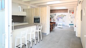 Eine moderne Küche mit einer zentralen Kochinsel, Barhocker und einem Essbereich mit einer Weltkarte an der Wand.