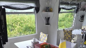 A compact living space with a dining area, a small kitchenette, and a window providing a view of greenery. - EXCLUSIVE MOBILE HOME
BASED IN COUNTRYSIDE BUT CLOSE TO AIRPORT AND TOWNS (Aldergrove)