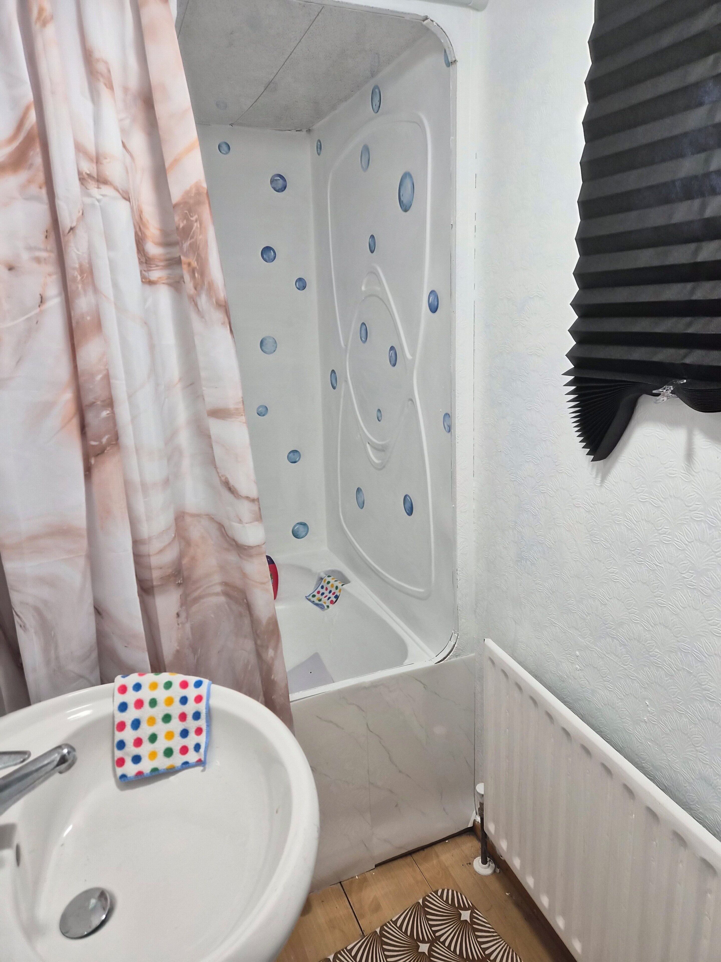 Une salle de bain avec une baignoire, un lavabo et un rideau de douche.
