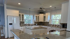 A kitchen with white cabinets, granite countertops, a built-in oven, a microwave, and a ceiling fan. - Skyline Surf View Villa Minutes to Downtown Jensen Beach and Local Beaches (Jensen Beach)