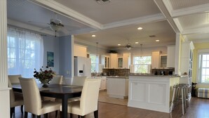 A spacious kitchen with white cabinetry, a dining area with a wooden table and chairs, and a central island. - Skyline Surf View Villa Minutes to Downtown Jensen Beach and Local Beaches (Jensen Beach)
