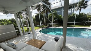 A covered outdoor seating area with a pool in the background. - Skyline Surf View Villa Minutes to Downtown Jensen Beach and Local Beaches (Jensen Beach)
