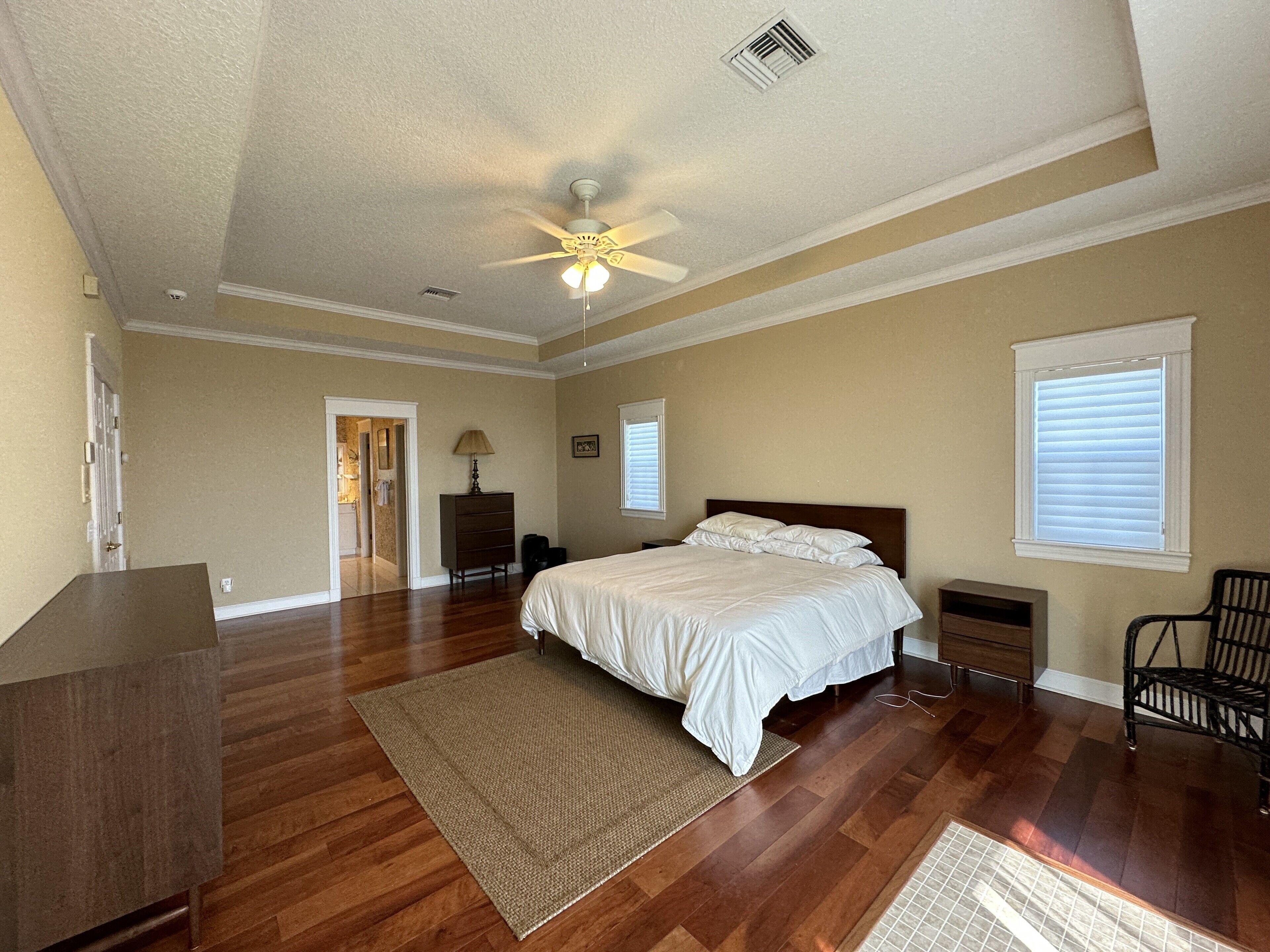 Ein Schlafzimmer mit Bett, Kommode und Deckenventilator.