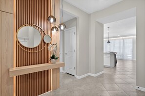 Ein modernes Interieur mit einer Holzvertäfelung, einem runden Spiegel und Pendelleuchten.