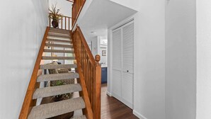 Una escalera con barandillas de madera y peldaños alfombrados que conduce a una habitación con una puerta blanca y una planta.