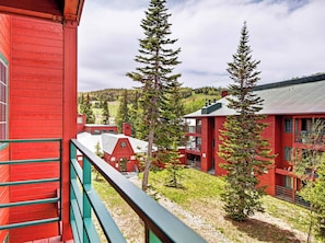 A red building with a balcony, surrounded by trees and a hilly landscape. - Giant Steps 45 Ski in/ Ski out (Brian Head)