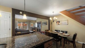 Eine Küche mit Granit-Arbeitsplatten, eine Essecke mit Tisch für vier Personen und ein Kamin.