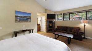 Ein Schlafzimmer mit einem Bett, Deckenventilator, Kamin, einer Couch und einem Fenster mit Blick.