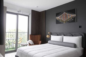 A modern hotel room with a large bed, a chair, a balcony with outdoor furniture, and a wall-mounted artwork. - Cozy 1-bedroom apartment in charming Accra with AC and gym (Accra)