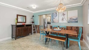 Een eetruimte met een houten tafel en stoelen, een kroonluchter en kunstwerken aan de muur.