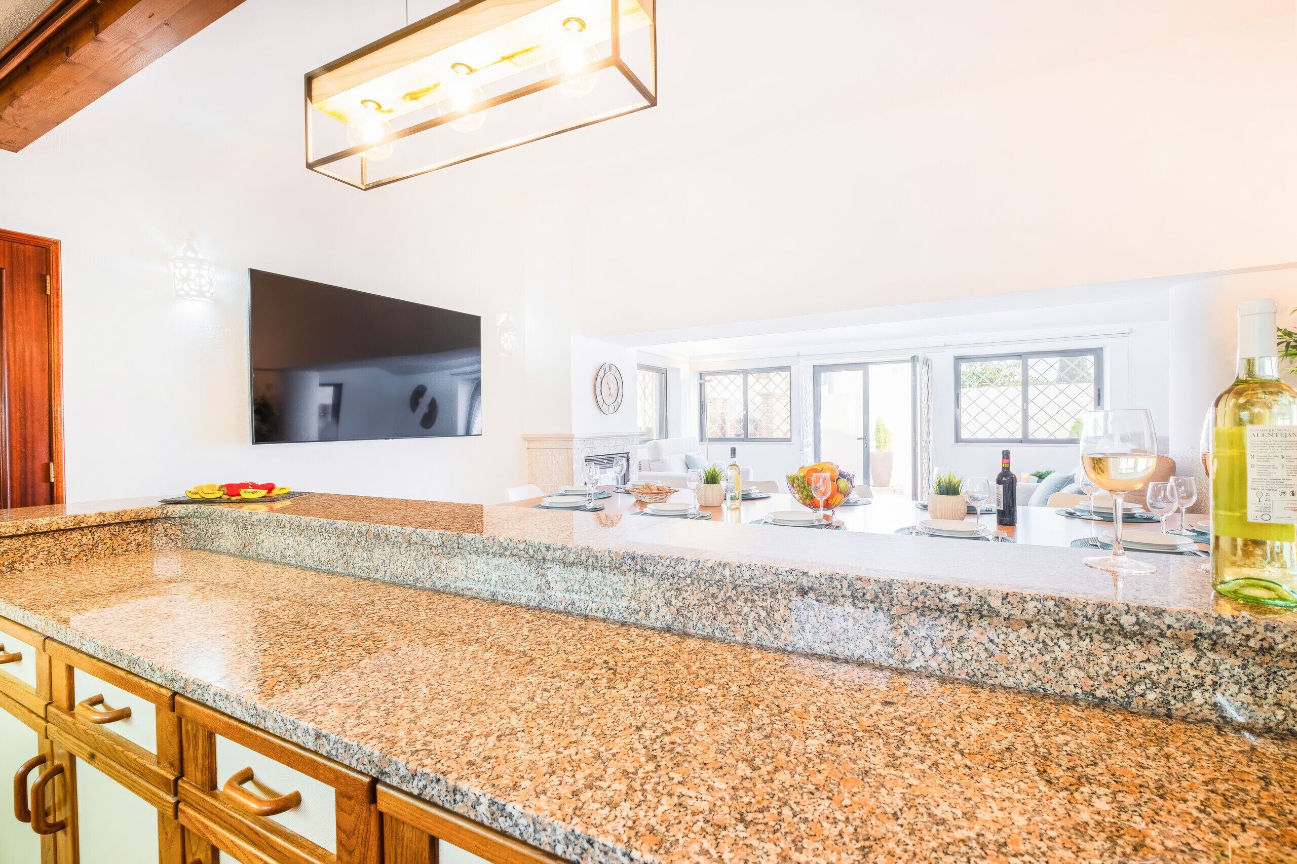 A modern kitchen with granite countertops, a built-in oven, and a large window overlooking a garden.