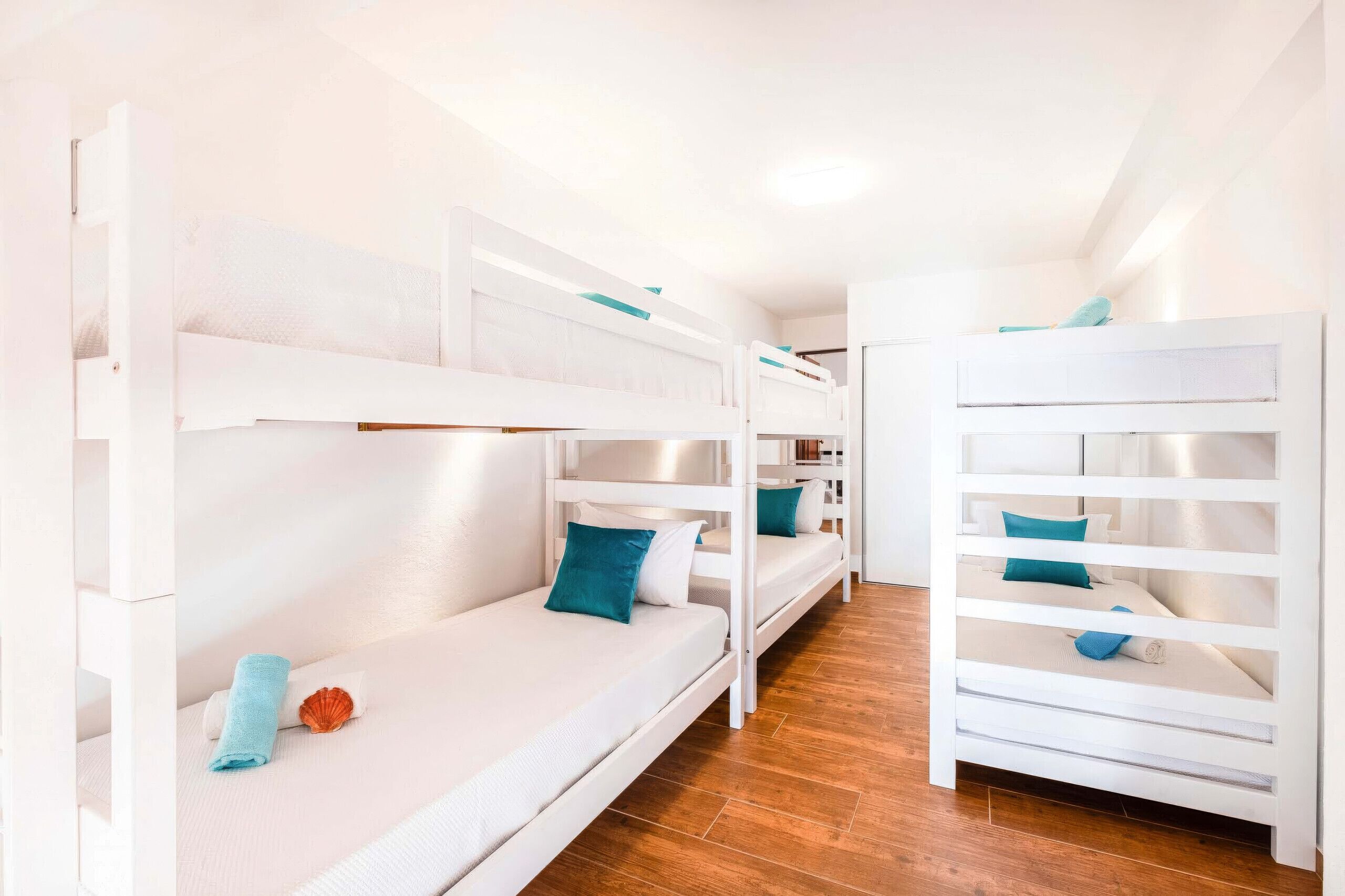 Habitación con literas, ropa de cama blanca y almohadas azules.
