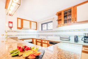 A kitchen with wooden cabinets, a built-in oven, a coffee maker, and a fruit bowl on the counter.