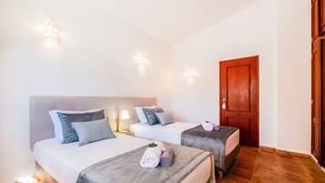 A hotel room with two beds, each with a headboard, bedside lamps, and towels.