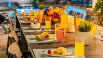 Mesa de comedor preparada con platos, cubiertos y diversas bebidas, como jugo y agua, en un ambiente de restaurante.