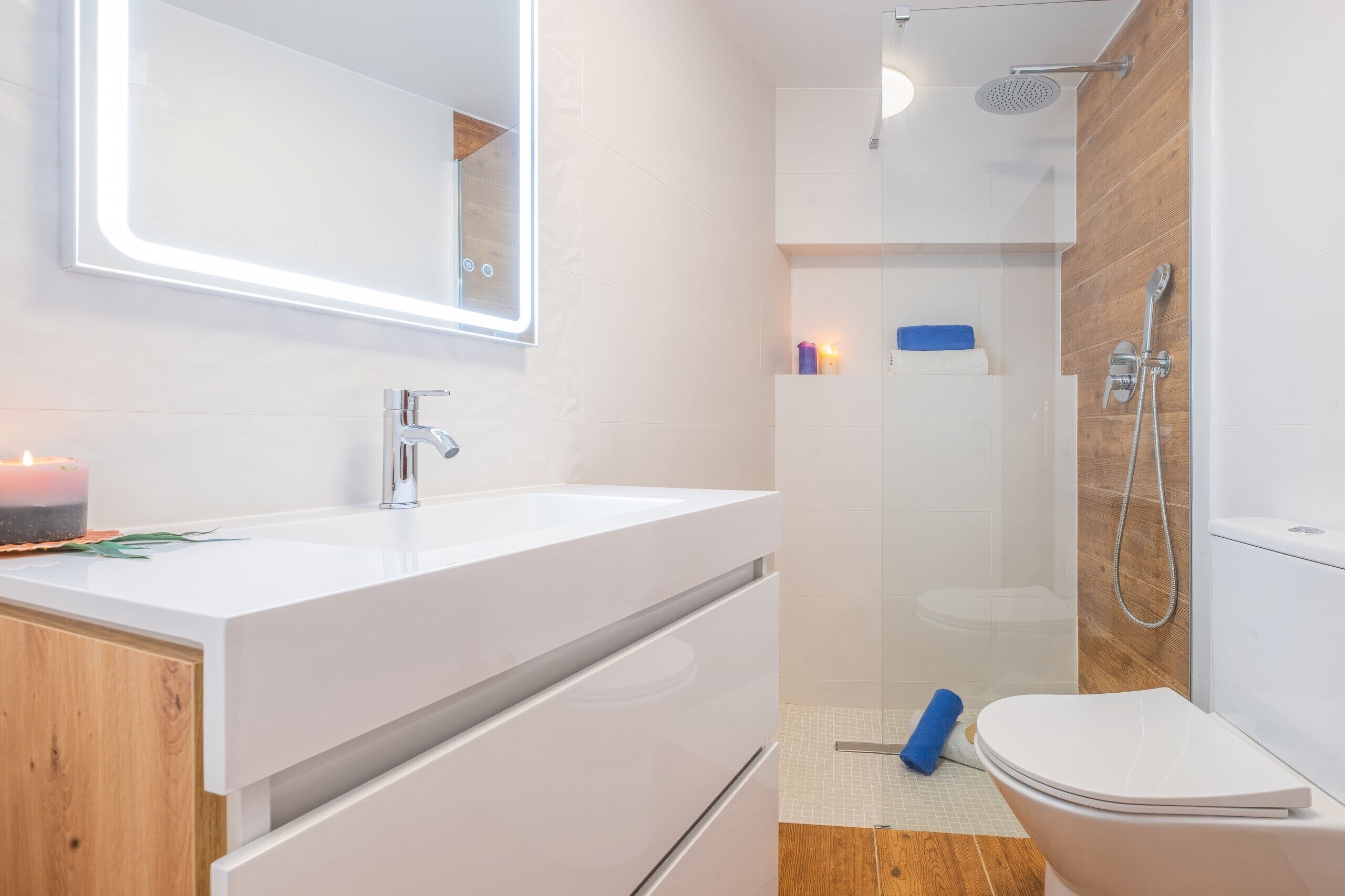 A modern bathroom with a white vanity, a mirror, a shower, and a toilet.