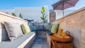 A cozy outdoor seating area with a built-in bench and cushions, a fire pit, and a large umbrella. - Luxury retreat w/ heatable pool & jacuzzi (Albufeira)
