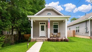 A single-story house with a front porch, a mailbox, and an American flag. - The Brainerd House · 3BR, EV Charger, Private Yard (Pensacola)