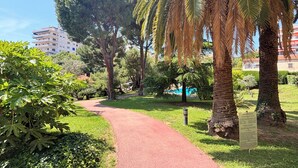 Ein Weg in einem Park mit Bäumen und einem Gebäude im Hintergrund.