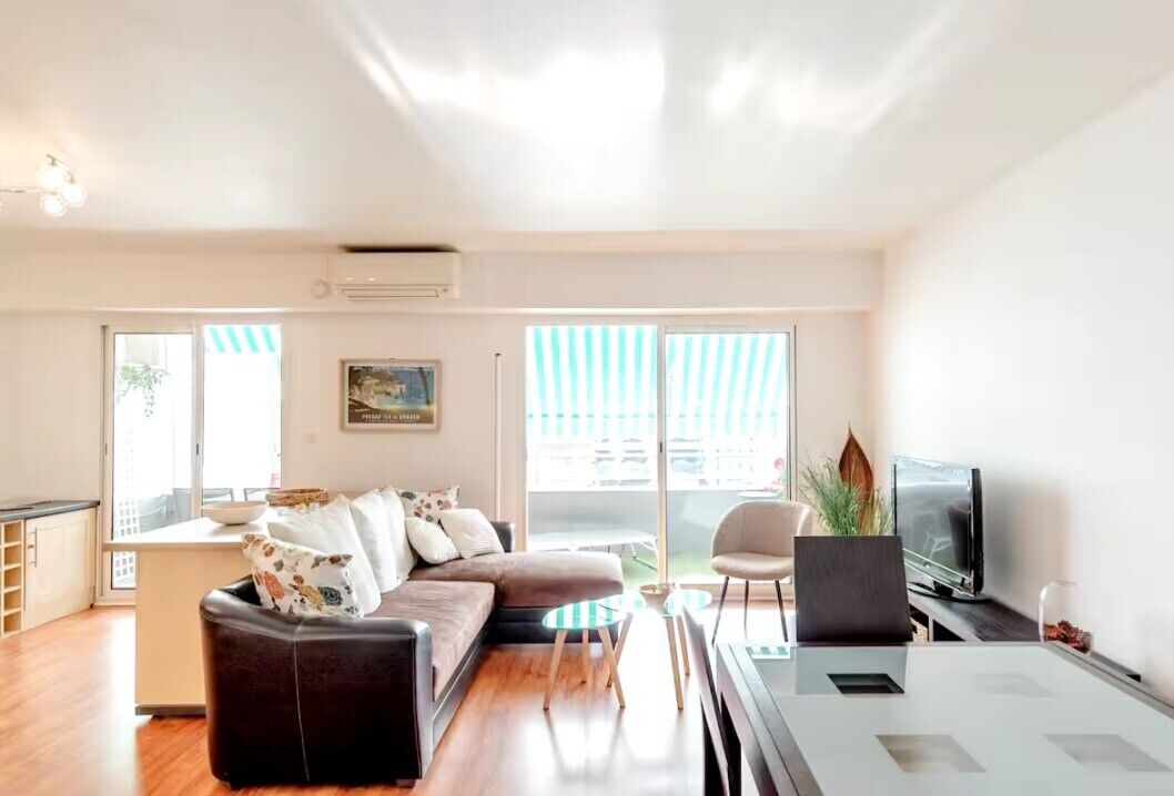Una sala moderna con un sofá, una mesa de centro, un televisor y un comedor.