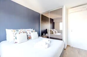 Ein Schlafzimmer mit Bett, Nachttisch, Spiegel und einer Schiebetür zum Badezimmer.