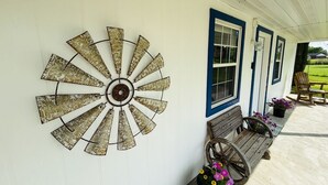 Une décoration en forme de moulin à vent sur une véranda, avec un banc et des plantes en pot.