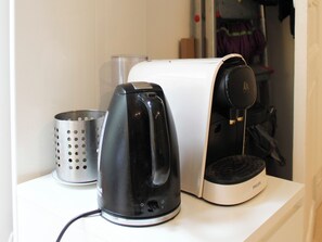 Ein Küchenbereich mit einer Kaffeemaschine, einem Wasserkocher und einem Toaster auf der Arbeitsfläche.
