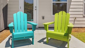 Two Adirondack chairs outside a house with a concrete patio. - Light on Lumen Beach Retreat (Panama City Beach)
