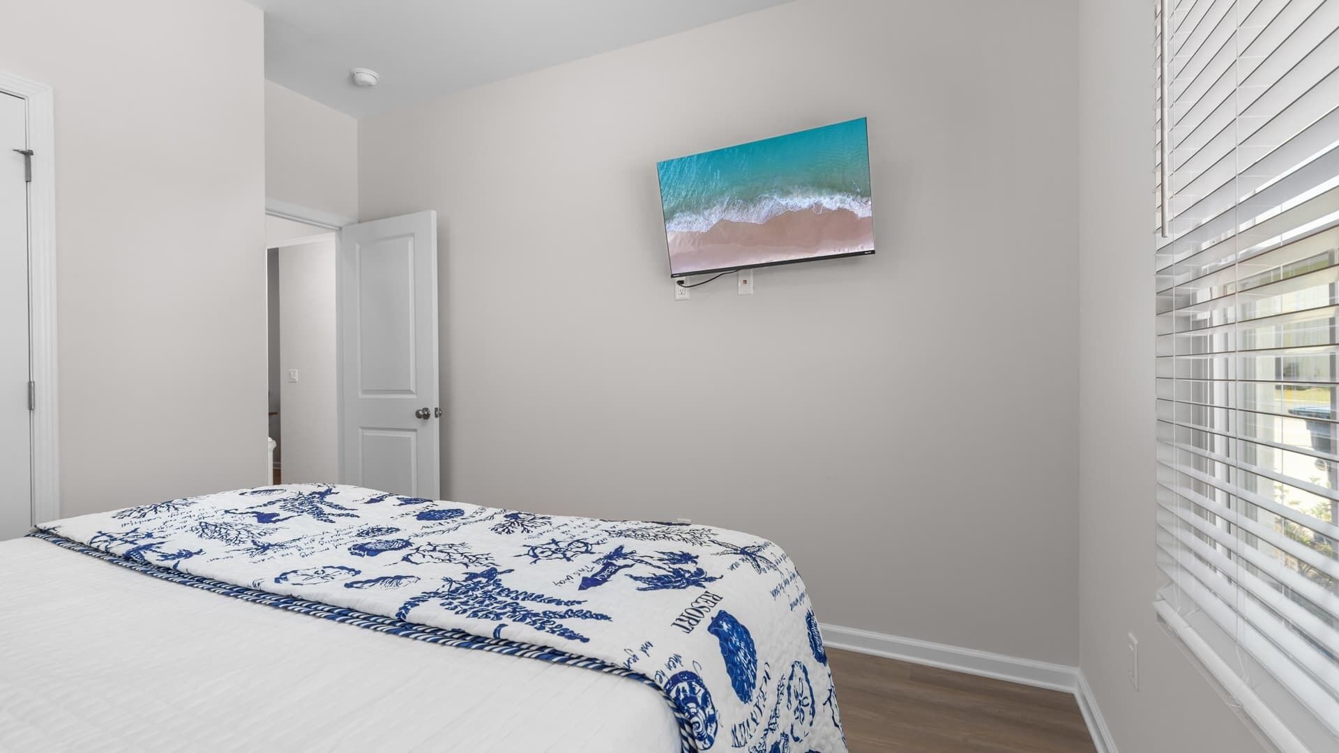 A bedroom with a bed, a door, and a wall-mounted painting.