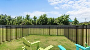 A fenced outdoor area with grass, a bench, and a small table.