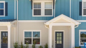 A multi-story residential building with a symmetrical facade, featuring a central entrance with a door and window, flanked by windows on both sides. - Light on Lumen Beach Retreat (Panama City Beach)